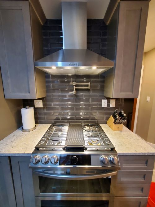 Navy blue tile backsplash behind kitchen range. 